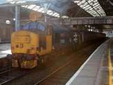 A mai cél a Cambrian Coast Line, ahol hétköznap még járnak mozdonyos szerelvények Carlisle és Barrow, néha Lancaster között. Most viszont a legnagyobb meglepetésemre már itt, Prestonban találkozunk a 37-essel és szerelvényével